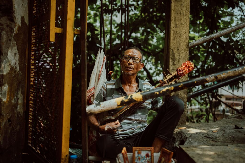 A musician playing a traditional stringed instrument beneath trees