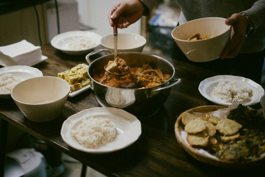 Hands serving from shared pots on a wooden table