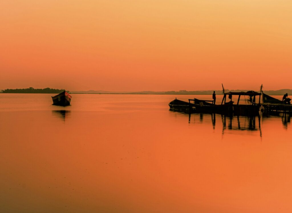 Silhouettes on a boat at Ggaba beach in golden light