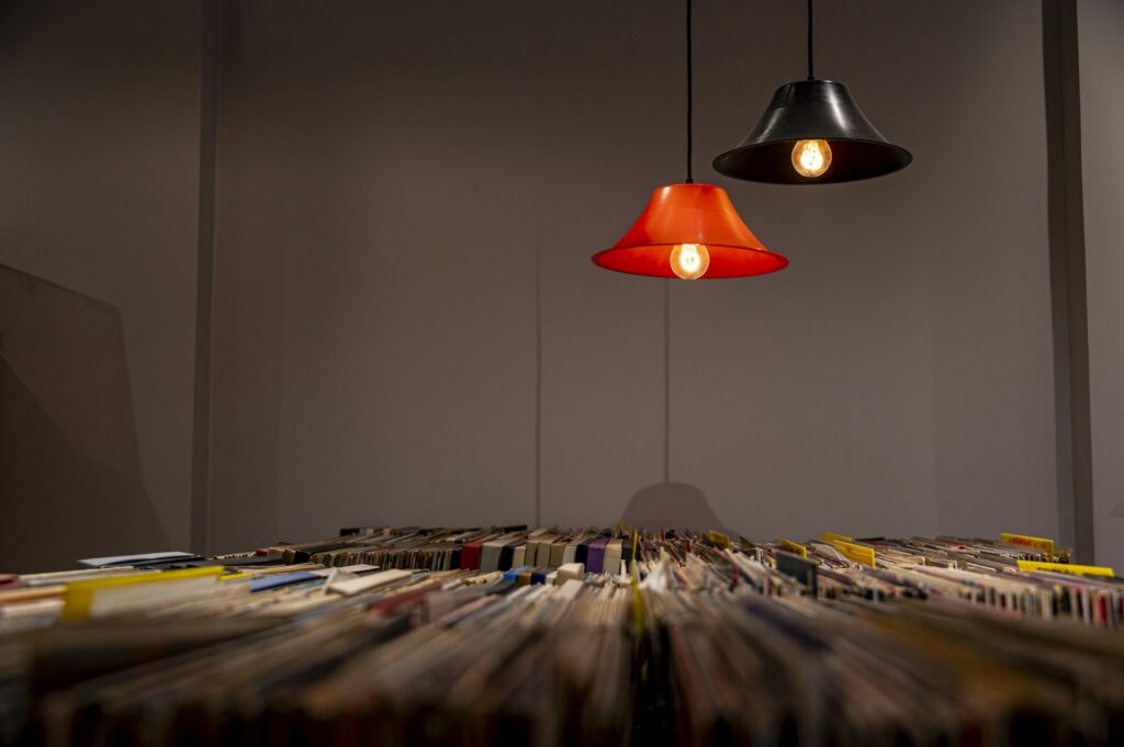 Shelves of vinyl records lit by two warm hanging lamps