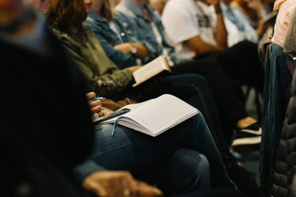 An audience listening closely with notebooks on their laps